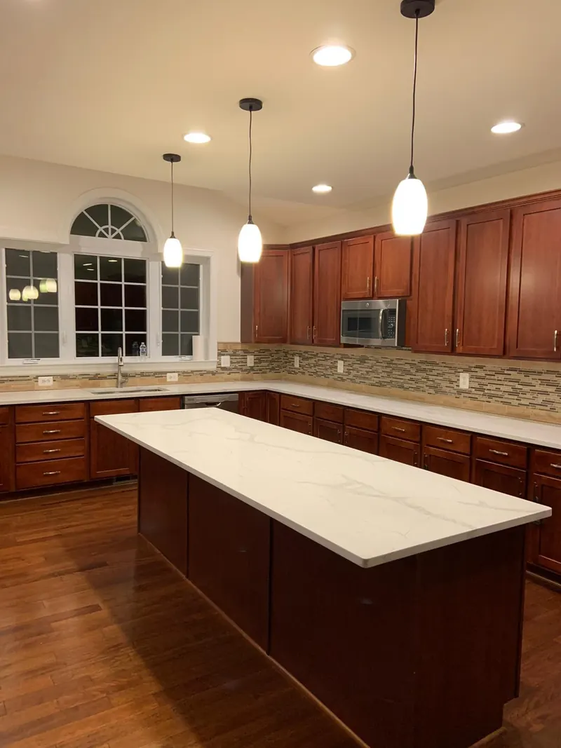 Calacatta quartz island and counters with cherry cabinets – installed by Beltway Countertops in Reston, VA