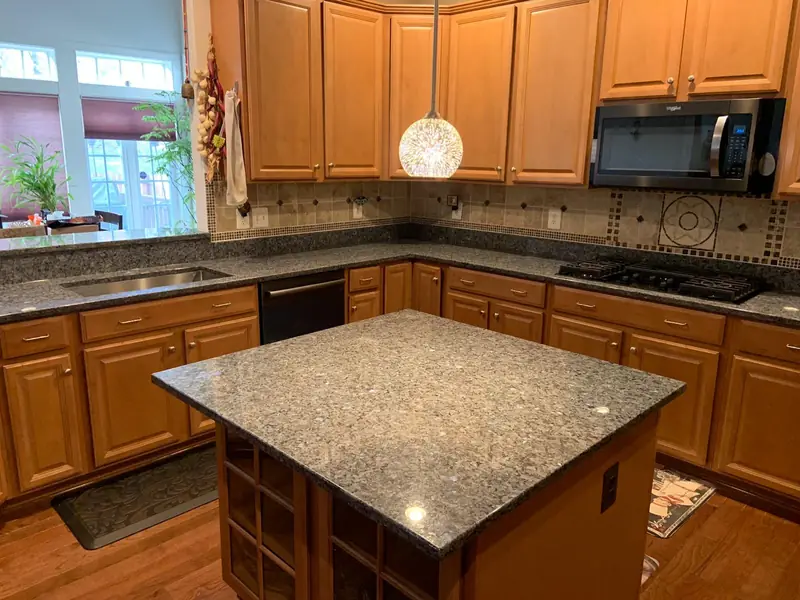 Dark blue-gray granite kitchen island with maple cabinets – installed by Beltway Countertops in Herndon, VA