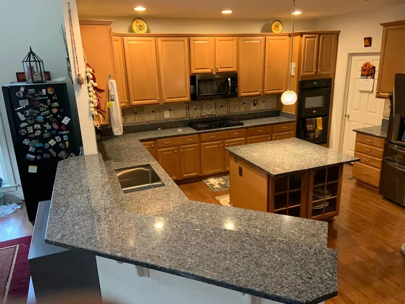 Dark granite kitchen with a raised bar and undermount sink – installed by Beltway Countertops in Herndon, VA