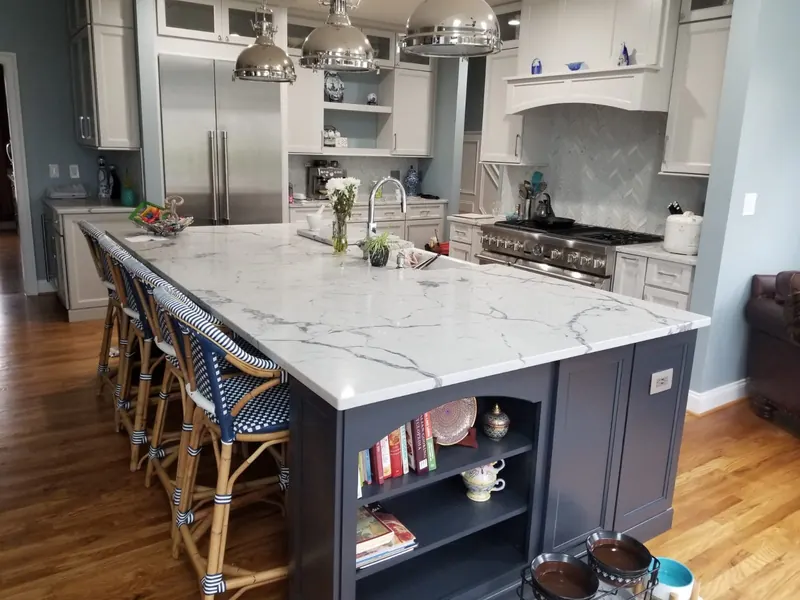 Marble-look quartz island with navy cabinets and a farmhouse sink – installed by Beltway Countertops in Ashburn, VA