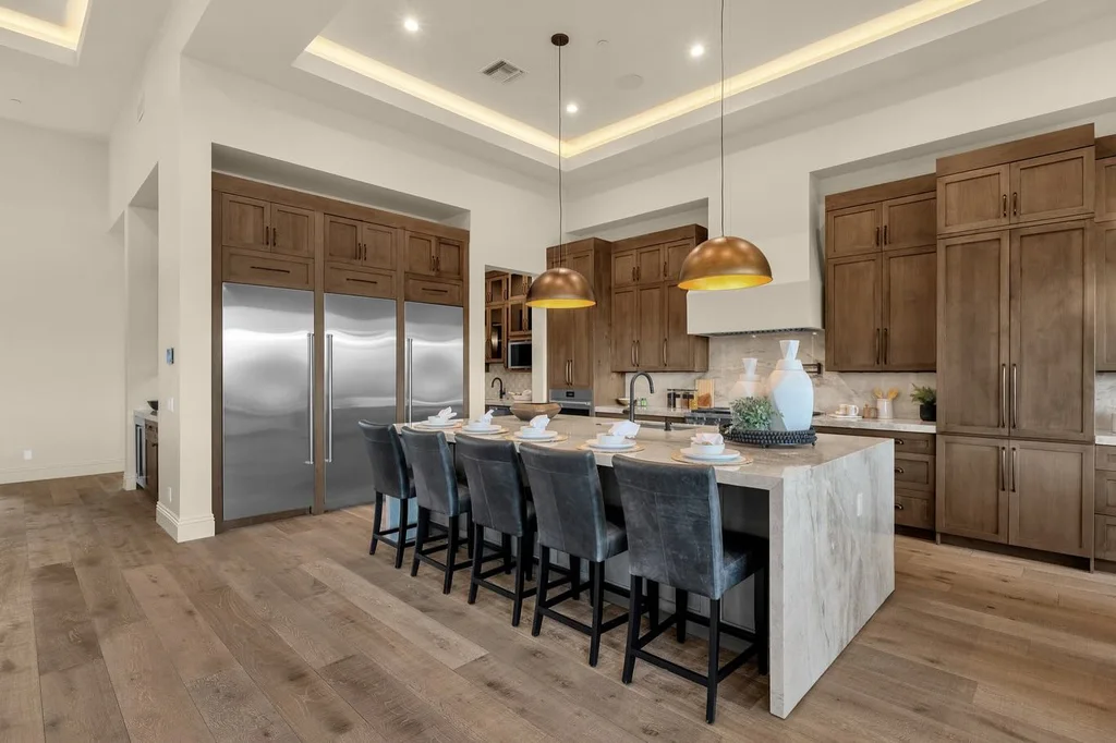Marble-look waterfall kitchen island with wood cabinets and stainless refrigerators, installed by Beltway Countertops in Ashburn, VA