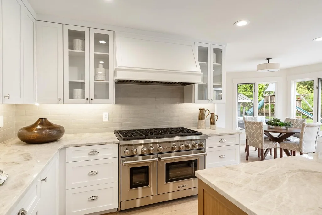 Taj Mahal-look countertops with white shaker cabinets and a stainless range, installed by Beltway Countertops in Chantilly, VA